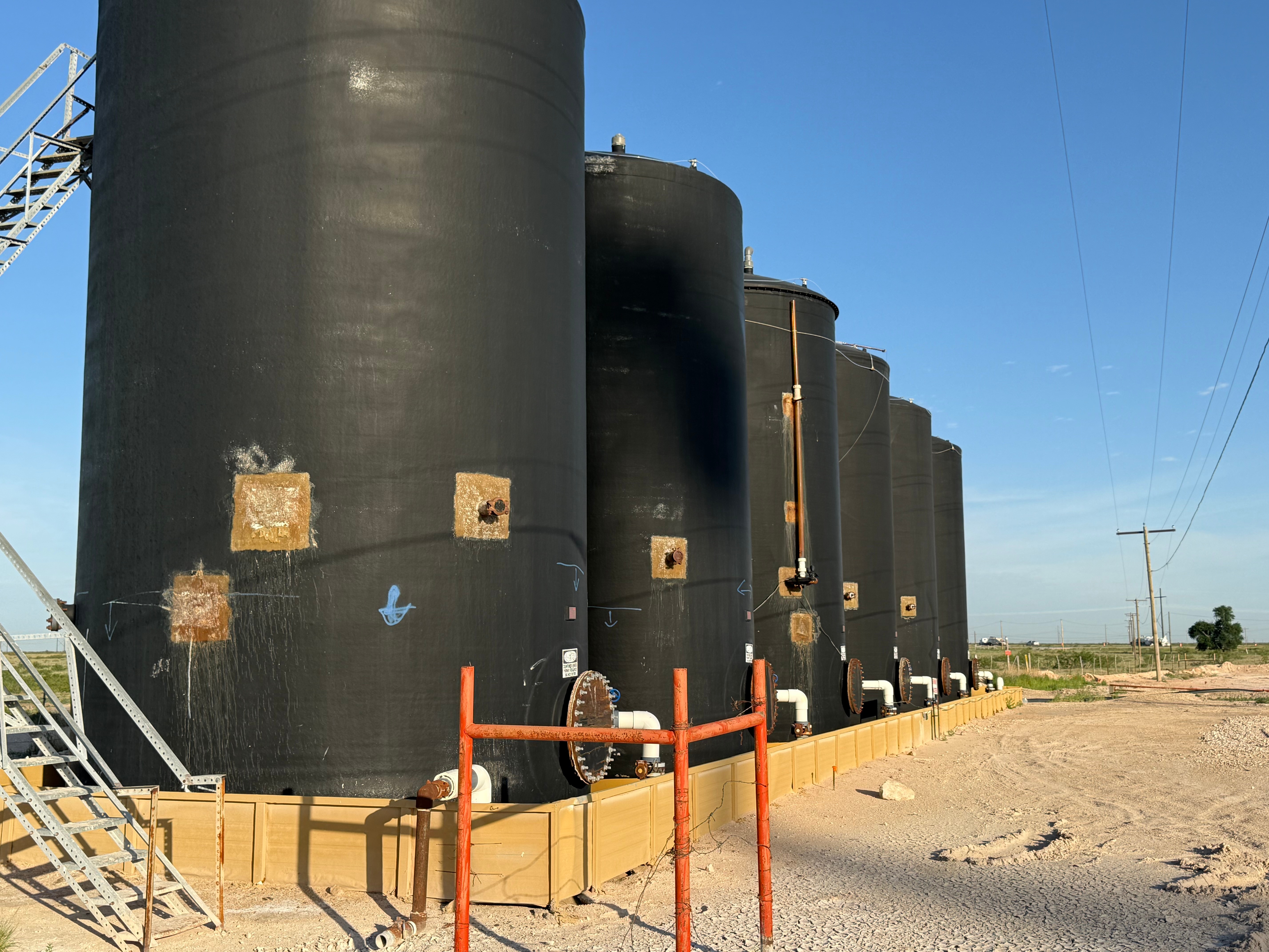Row of black brine storage tanks with containment berm at the Salty Dog Brine facility